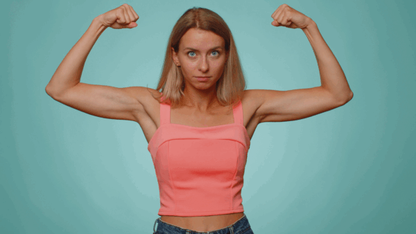 I am strong and independent. Woman showing biceps, looking confident, feeling power strength to fight for rights, energy to gain success win. Young adult girl isolated on blue studio wall background